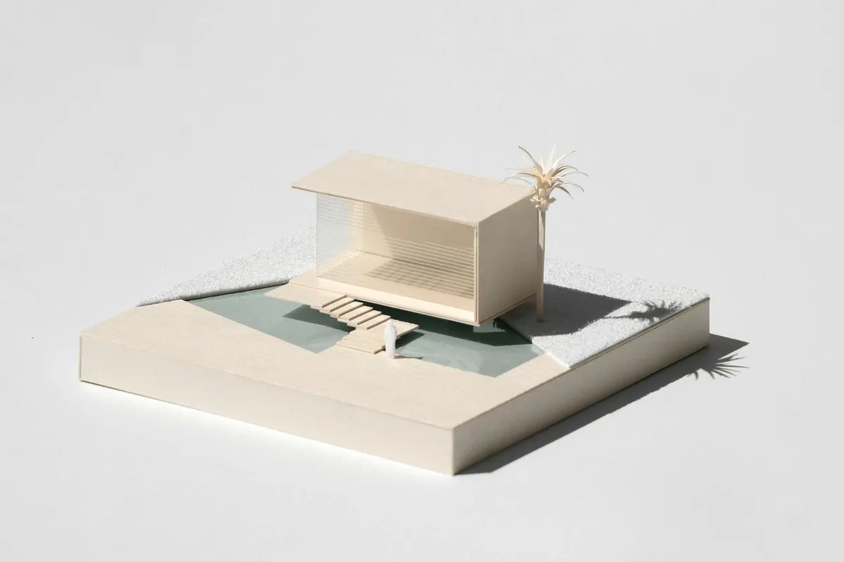 A small white house model sitting on top of a closed hardback book.