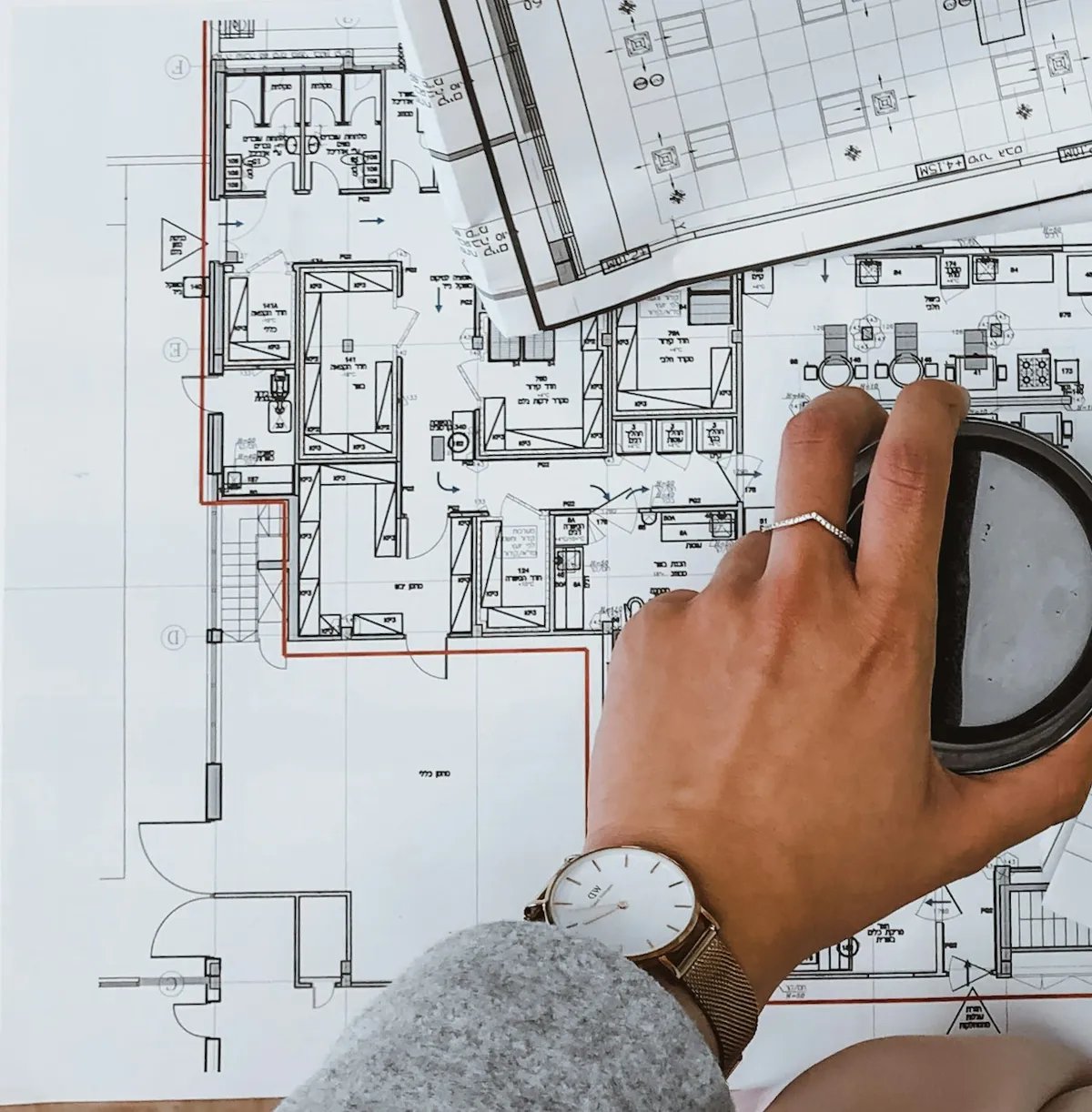 A printed plan on a desk showing floor plan symbols such as grid bubbles, door swings and a level triangle.