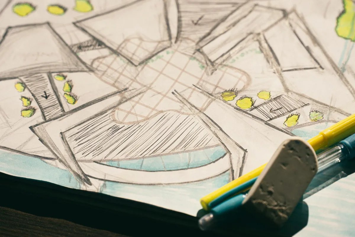 A pencil floor plan sketch with yellow marker trees, and a pen and an eraser lying on top.