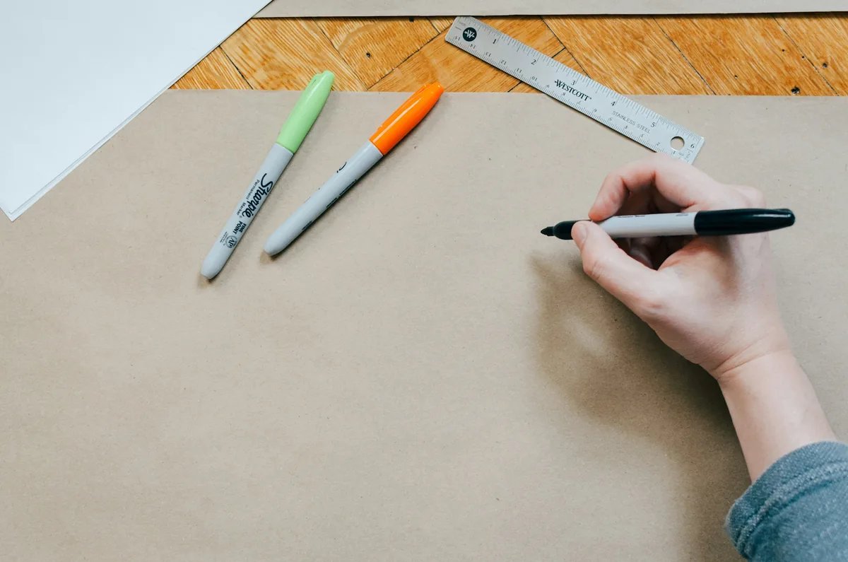 A marker sketch on brown kraft paper, with two markers and a steel ruler beside it.